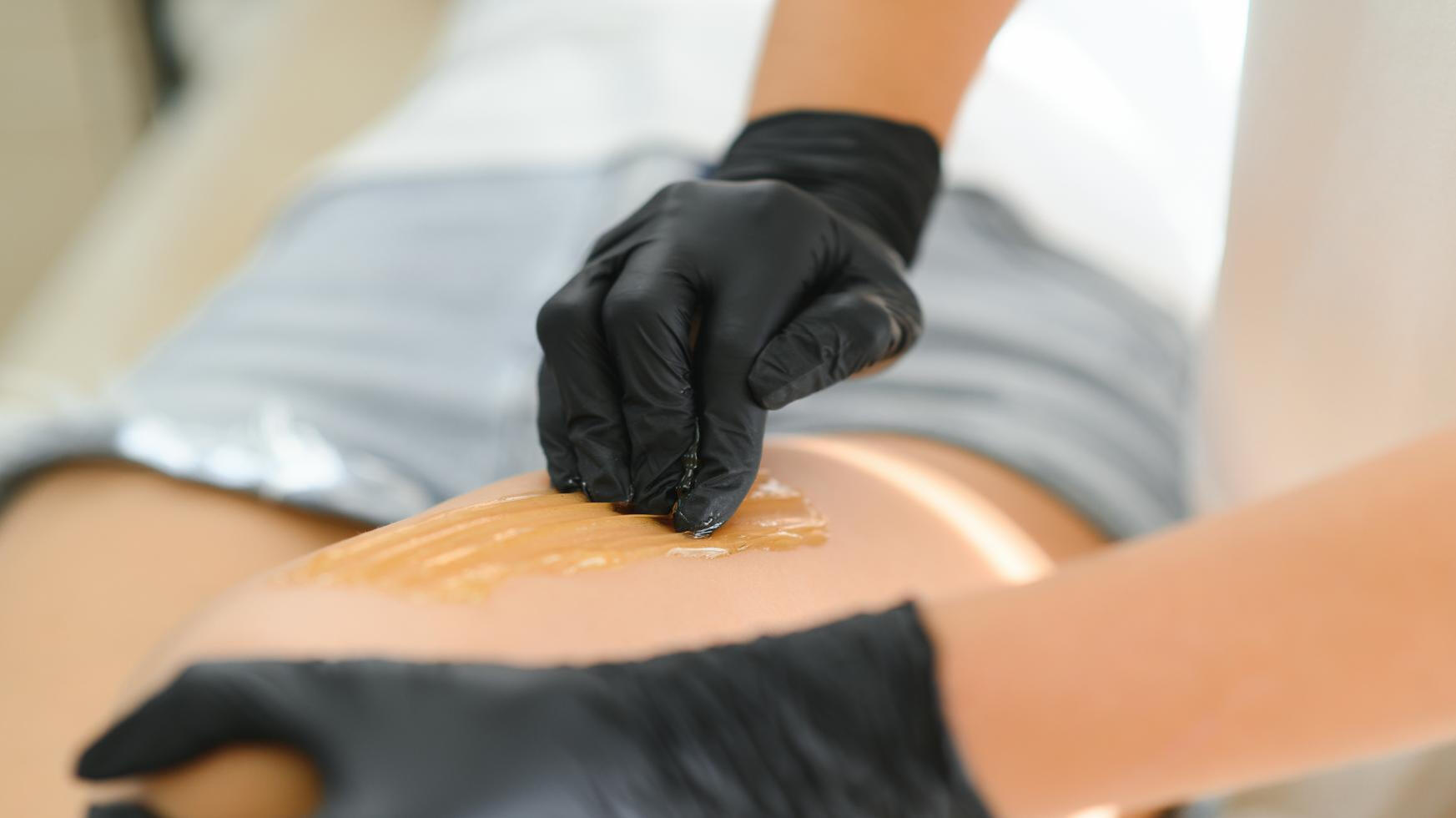 Woman applying sugar paste to leg